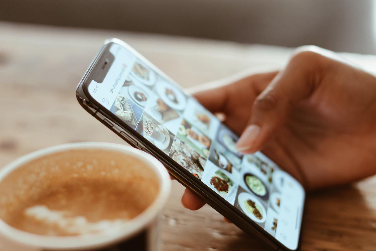 Person scrolling Instagram on a phone with coffee